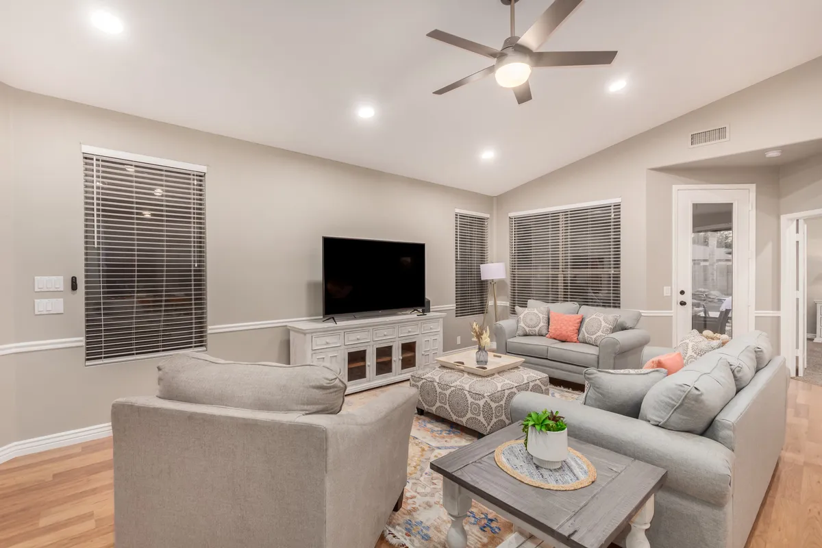 A cozy living room with a comfortable sofa set, coffee table, television, and tasteful decorative items. The ambient lighting and layout suggest a welcoming space where families and remote workers can relax, gather, or work.