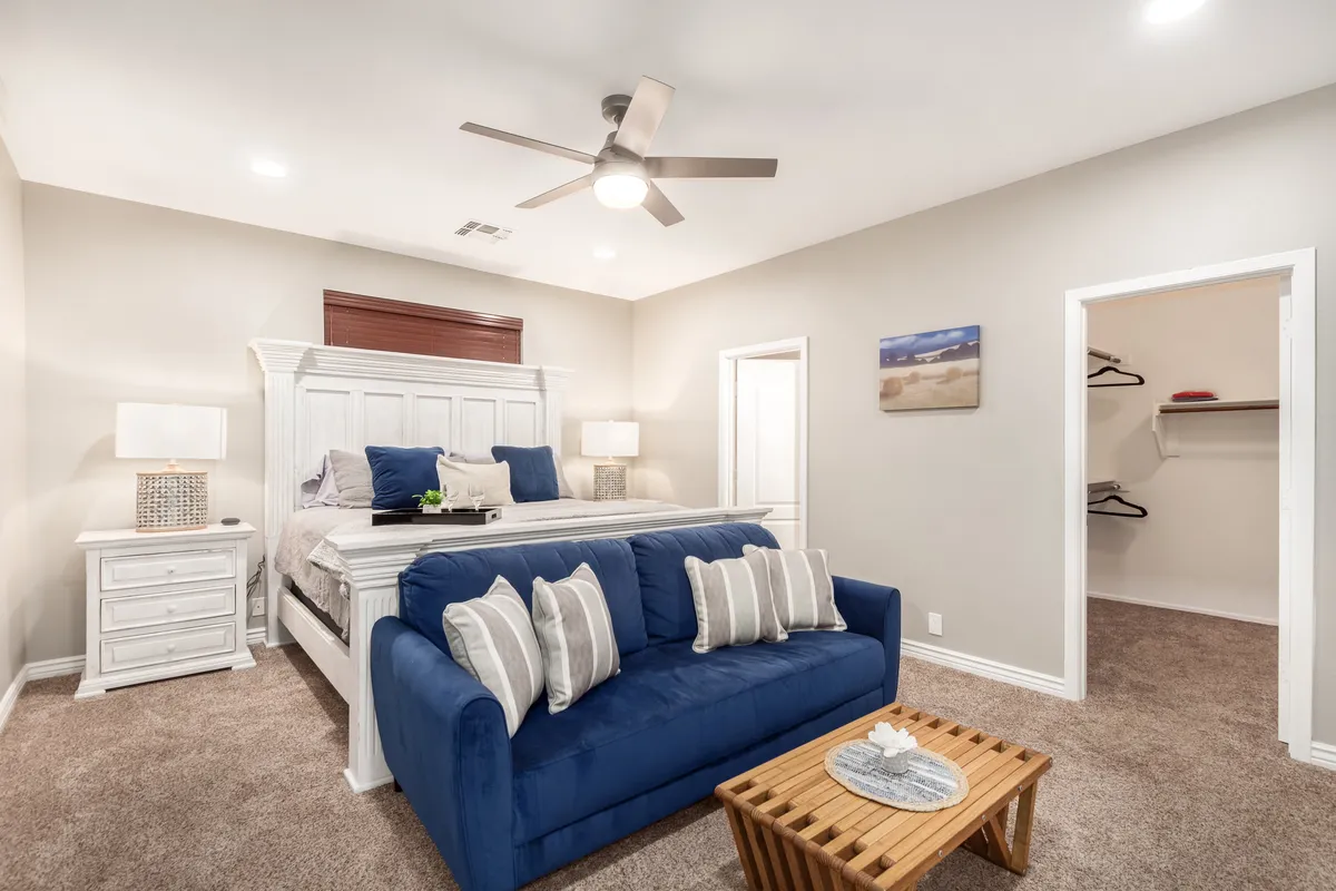 A serene bedroom featuring a cozy bed, a sofa for lounging, a nightstand with decor, and soft lighting, suggesting both comfort and a space for relaxation or conversation. The ambiance is tranquil and inviting, ideal for unwinding.