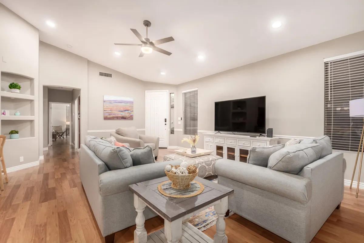 A cozy living room featuring comfortable seating, a stylish TV unit, decorative art, and a central coffee table, set up for relaxing, socializing, or unwinding after a day out.