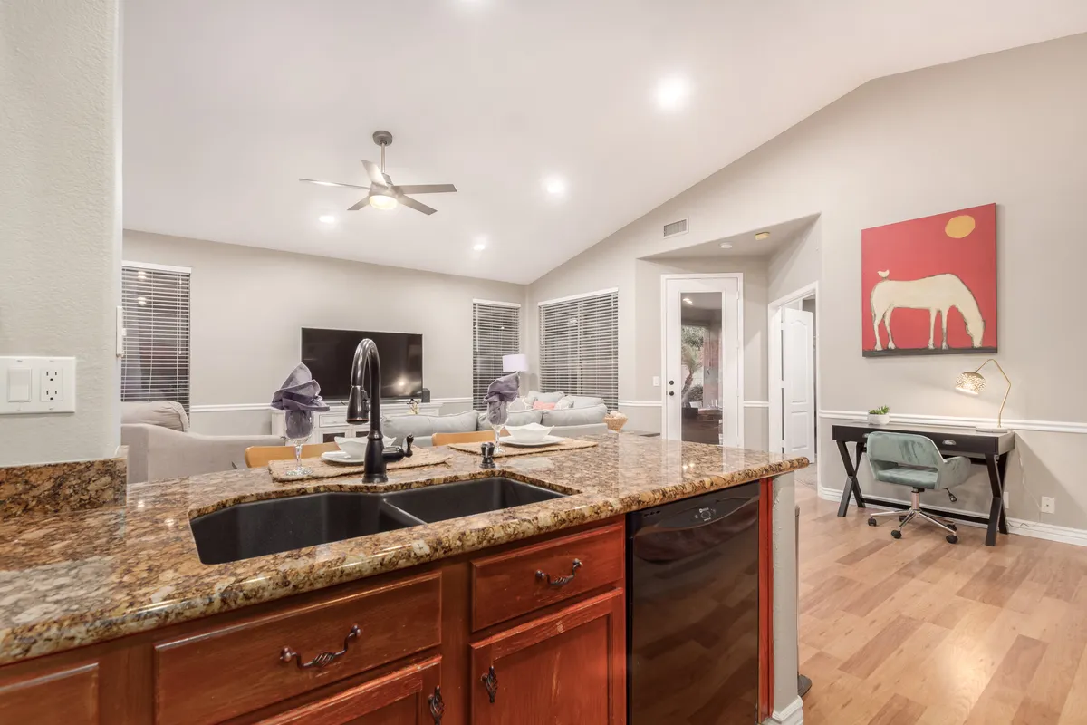 A view from the kitchen island with granite countertop overlooking the adjacent living area, tying together the kitchen, living, and workspaces in an open-plan layout. Artwork and cozy furnishings invite relaxation and creativity.
